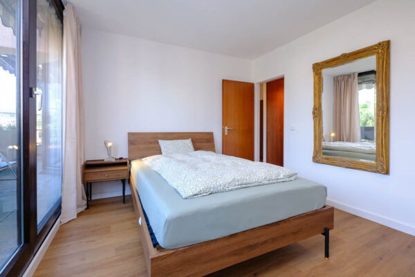 Schlafzimmer Blick auf 140cm Bett, Nachttisch und Spiegel